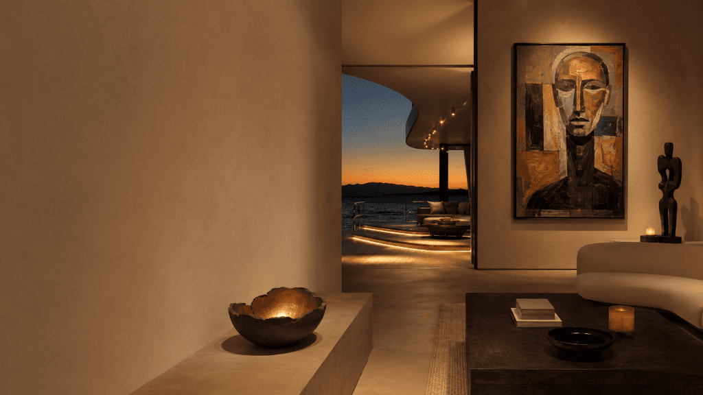 A sunset-lit interior with a large abstract portrait and a carved figure on a side table